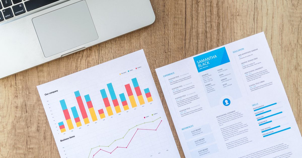 Bureau avec ordinateur ouvert sur un CV professionnel et une calculatrice posée à côté