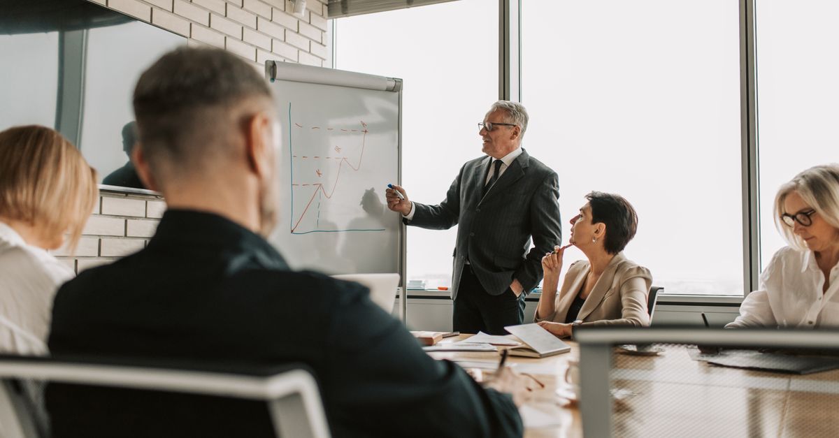 Salle de réunion avec tableau de présentation stratégique, consultants autour d'une table de travail
