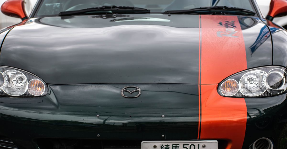 Mazda MX-5 rouge sur route sinueuse de montagne, illustrant la philosophie Jinba Ittai de la conduite sportive
