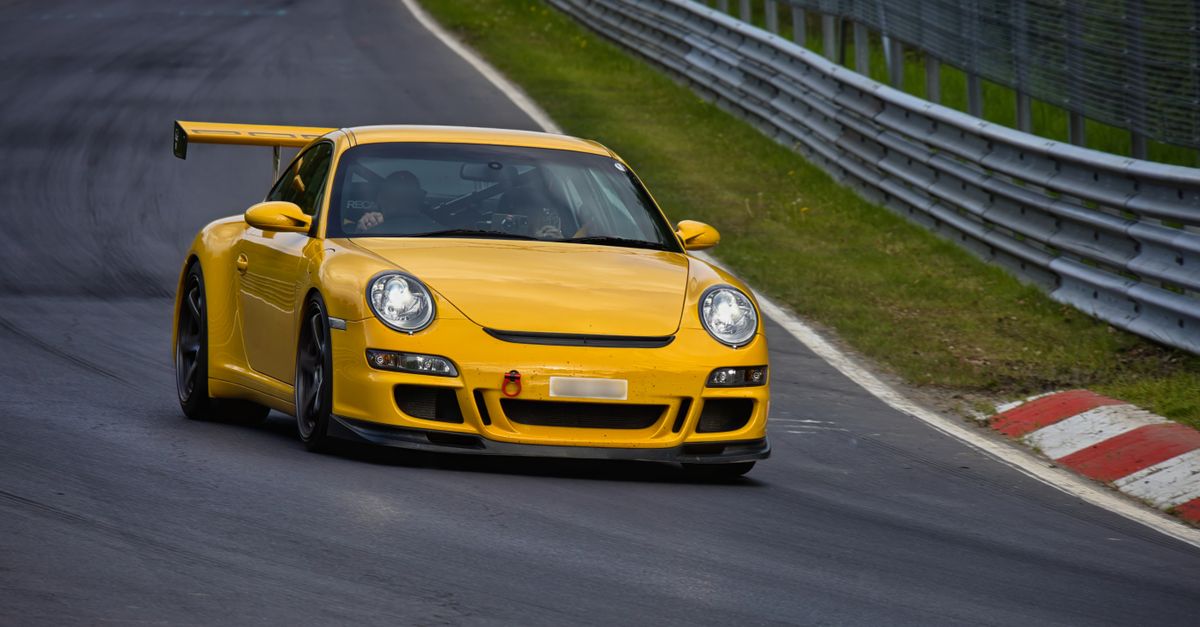 Porsche 911 rouge sur une route de montagne sinueuse au coucher du soleil, symbole de performance et élégance