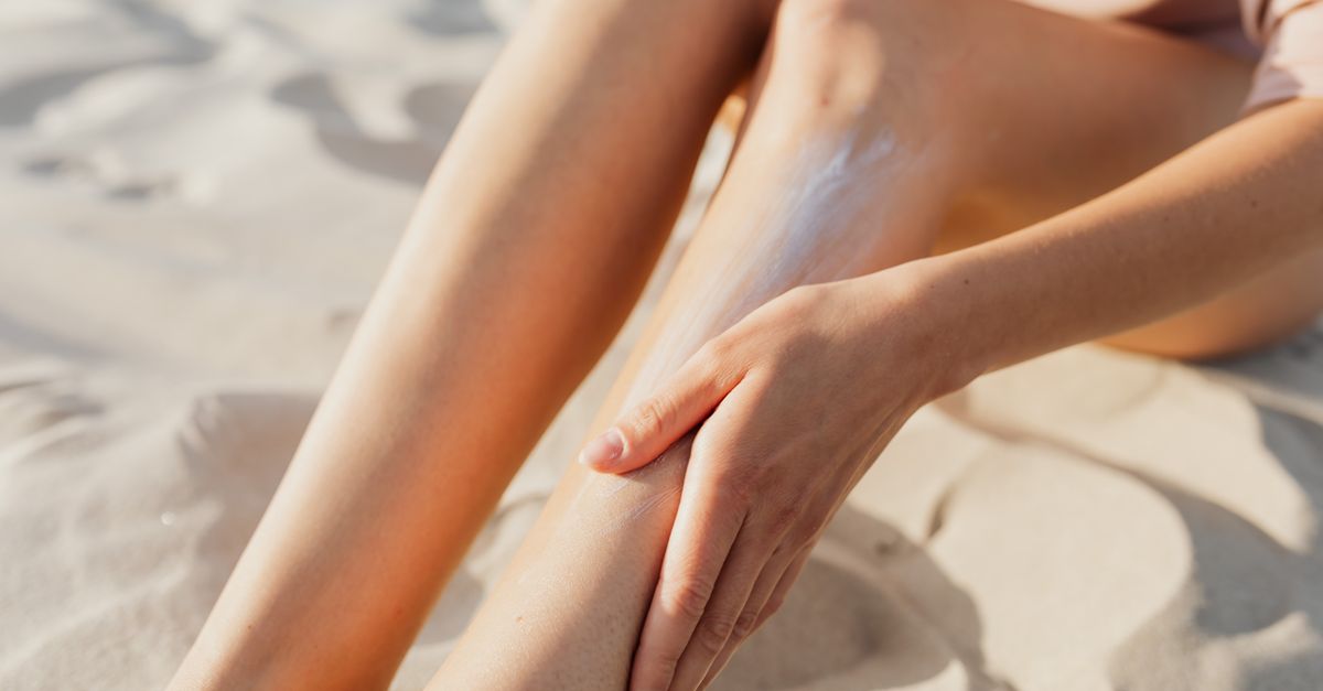 Flacon de crème solaire posé sur une serviette de plage avec des lunettes de soleil