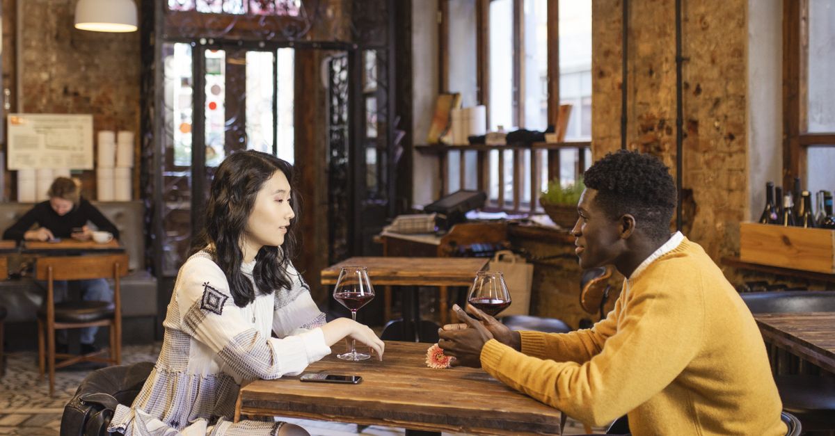 Couple souriant partageant un café lors d'un premier rendez-vous en terrasse