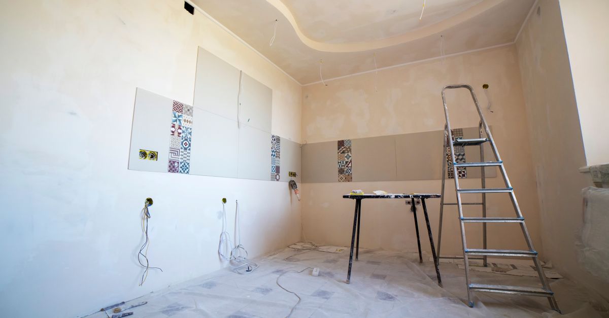 Pose de papier peint sur un mur avec brosse à maroufler pour chasser les bulles d'air