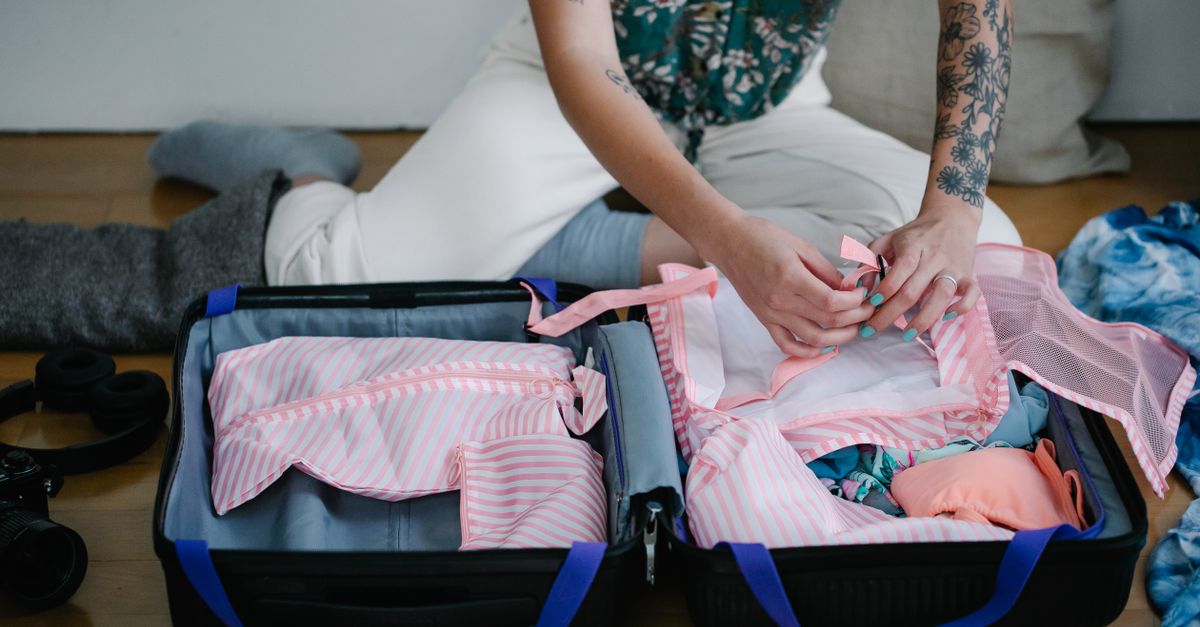 Valise cabine ouverte remplie de vêtements pliés et d'accessoires de voyage