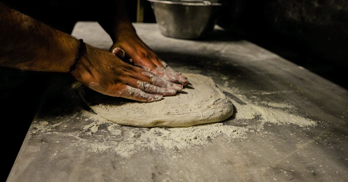 Pâte à pizza maison étalée sur un plan de travail fariné