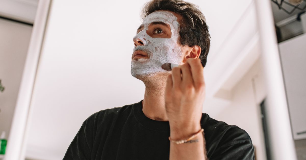 Homme appliquant un soin sur son visage devant un miroir